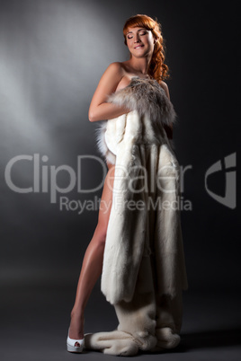 Pretty smiling nude girl posing with fur coat