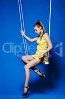 Beautiful girl with disco makeup posing on swing