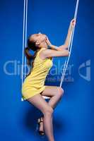 Sensual young model with UV makeup posing on swing