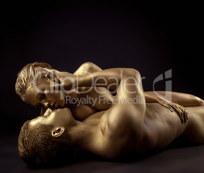 Naked lovers posing as golden statues come to life