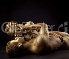 Naked lovers posing as golden statues come to life