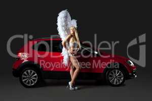 Pretty slim girl in angel costume posing with car