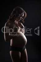 Studio shot of smiling topless pregnant woman