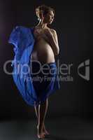 Pretty pregnant woman posing with flying cloth
