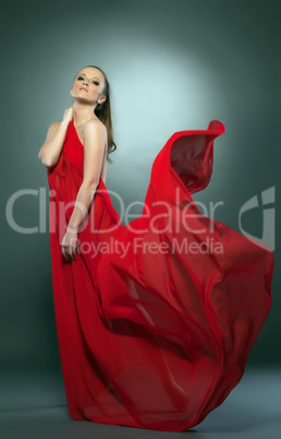 Graceful naked girl posing in red flying cloth