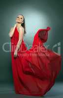 Graceful naked girl posing in red flying cloth