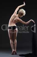 Flexible young woman dancing topless with cloth