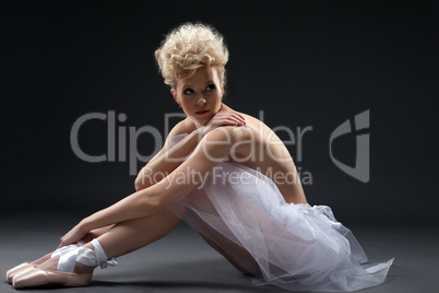 Shot of curly blonde ballerina posing in studio