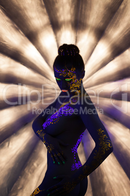 Sexy nude girl with glowing pattern under UV light