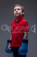 Thoughtful young boy posing in boxing gloves