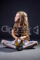 Cute curly-haired little girl posing with ball