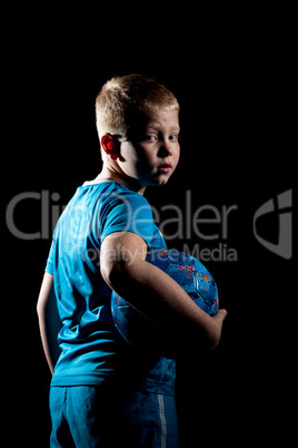 Portrait of sporty boy with ball isolated on black