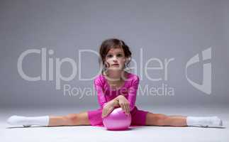 Adorable little gymnast posing on split in studio