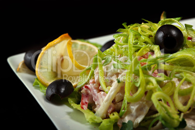 Delicious salad garnished leek, lemon and olives