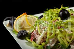 Delicious salad garnished leek, lemon and olives