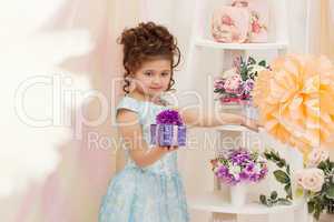 Cute girl posing with gift box in decorated studio