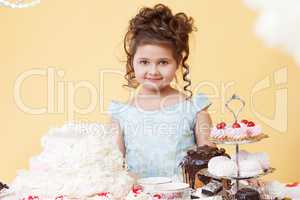 Pretty smiling girl posing at table with desserts