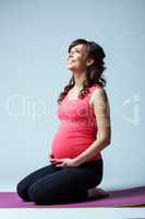 Charming pregnant woman happily smiling in studio