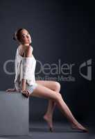 Attractive young model posing sitting on cube