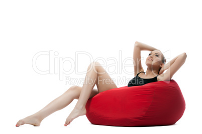 Image of relaxed young girl lying on red ottoman