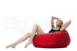 Image of relaxed young girl lying on red ottoman