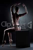 Image of muscular topless dancer sitting on cube