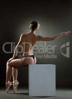 Graceful topless girl posing sitting on cube