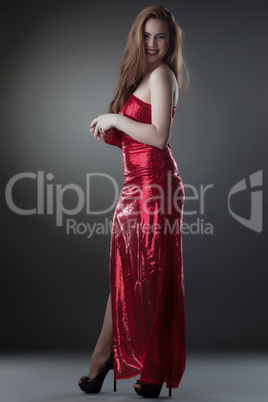 Beautiful smiling model posing in long shiny dress