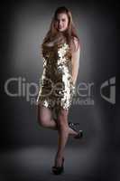 Seductive young girl posing in shiny golden dress