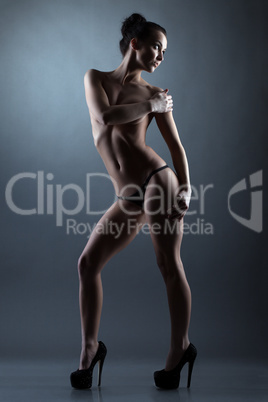 Slender graceful model posing topless in studio