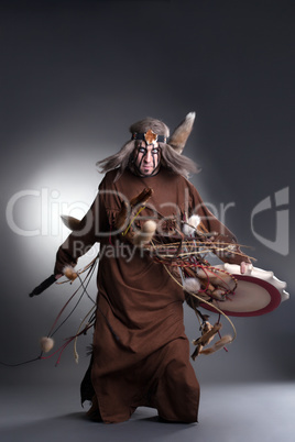 Shaman posing with tambourine, on gray background