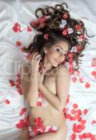 Satisfied naked girl posing nude with rose petals