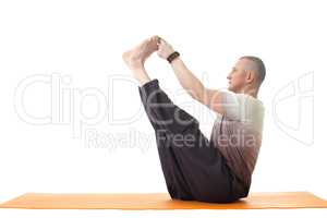 Middle aged man doing yoga in studio. Side view.