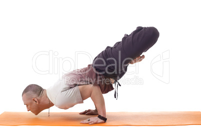 Focused athletic man posing in difficult yoga pose