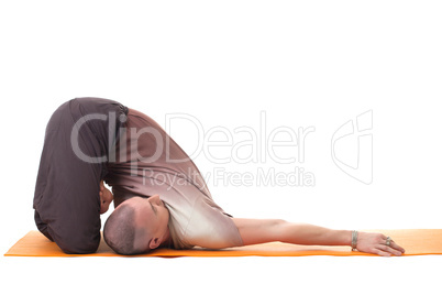Flexible muscular man practicing yoga in studio