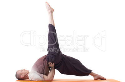 Flexible man practicing yoga exercises in studio