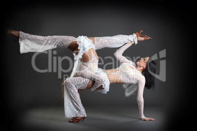 Duet of flexible slim dancers posing in studio
