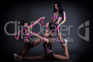 Trio of alluring dancers posing with pink rope