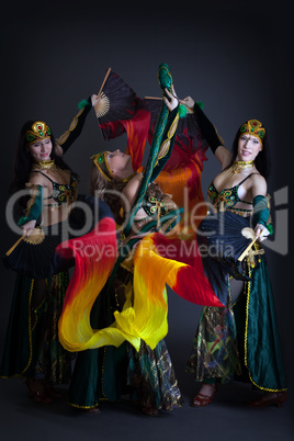 Graceful belly dancers posing with colorful fans