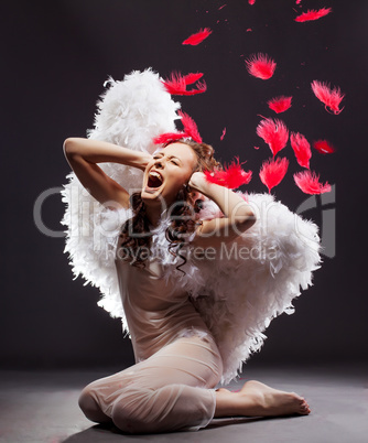 Attractive woman dressed as angel cries in studio