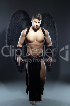 Handsome muscular guy posing as fallen angel
