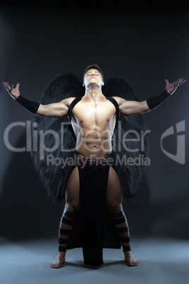 Young muscular man posing as fallen angel