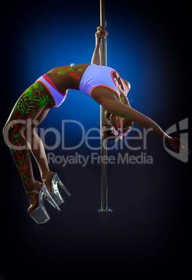 Seductive pole dancer exercising stretching