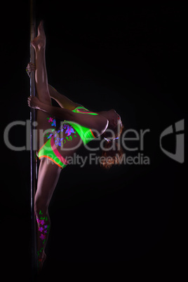 Flexible girl dancing on pole under UV light