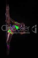 Flexible girl dancing on pole under UV light