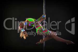 Graceful red-haired young woman dancing on pole