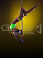 Graceful pole dancer posing under UV light