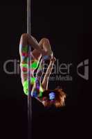 Flexible young dancer posing curled up on pylon