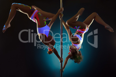 Sporty girls dancing on pole under UV light
