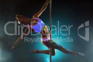 Pretty girl with luminous makeup dancing on pole